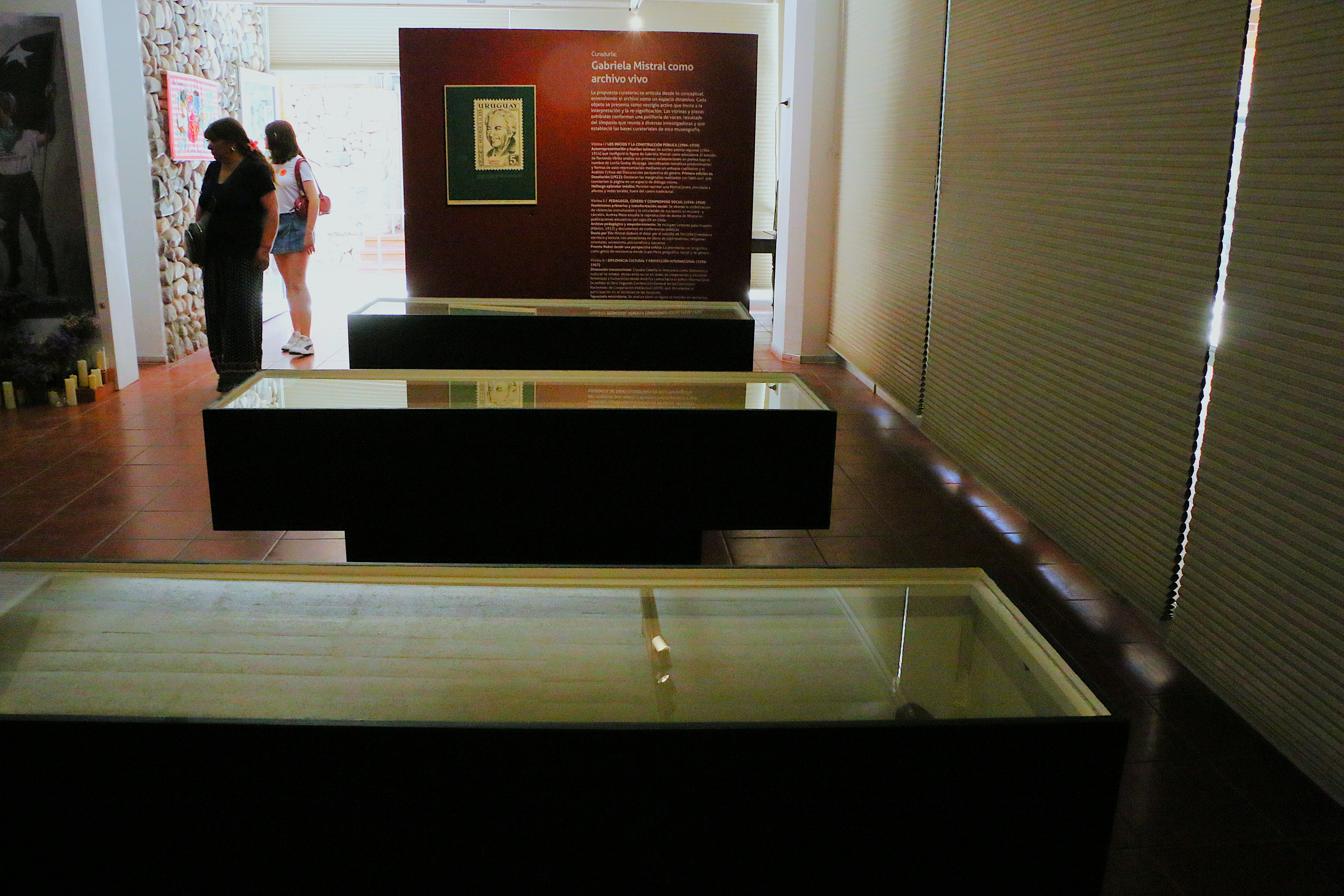 Vitrinas de la exhibición junto a texto curatorial en muro falso