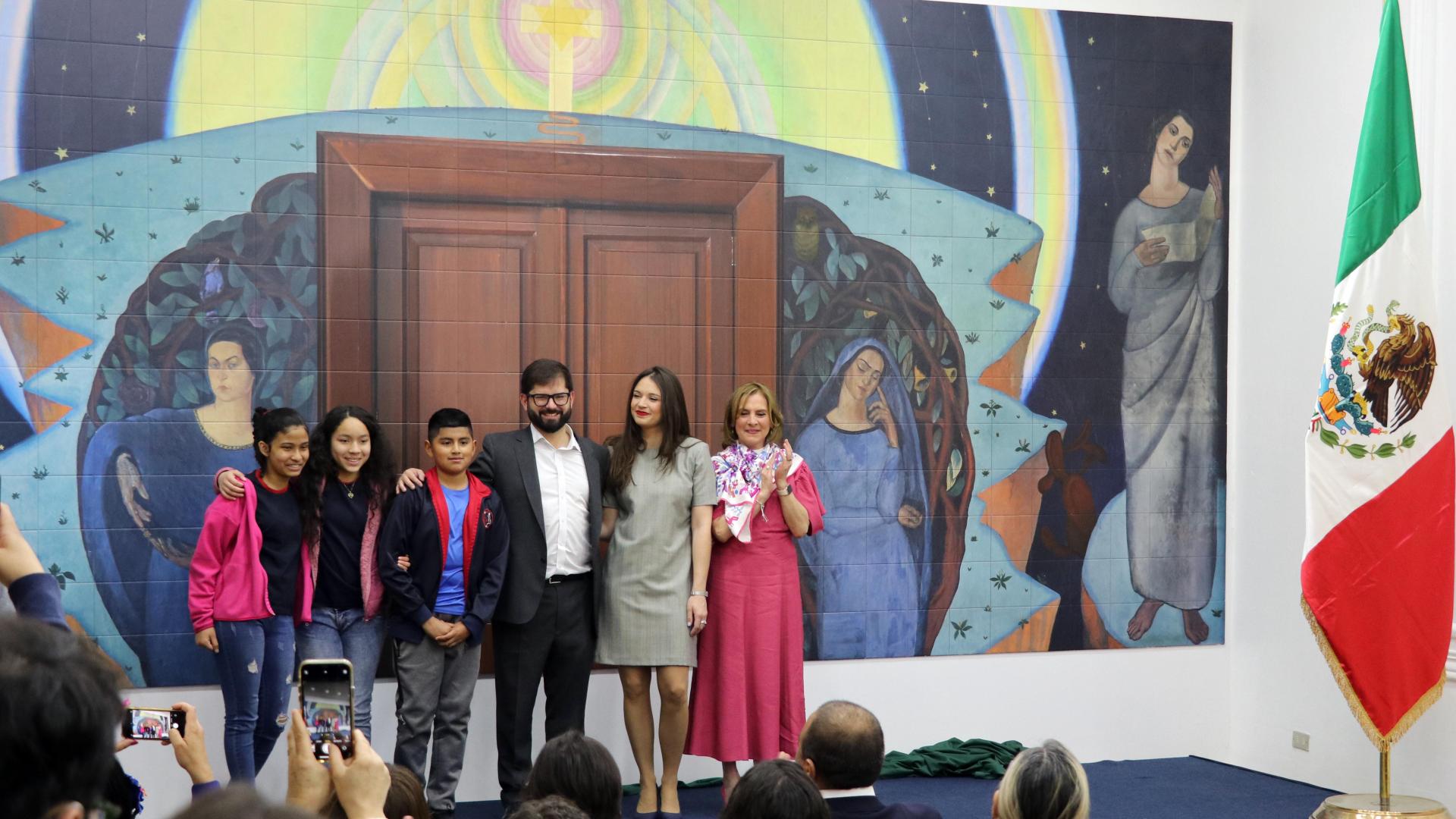 Foto de un grupo de personas, adultos y niños frente al mural que estaba siendo inaugurado.