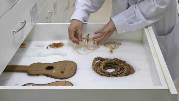 Manos acomodan pieza textil -cordón de fibras naturales- en un cajón especialmente acondicionado
