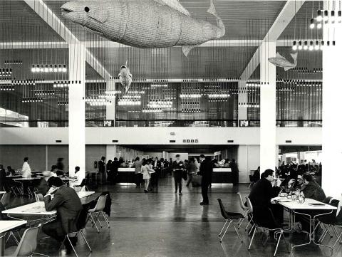 Imagen en blanco y negro del edificio de la UNTAD III que muestra un gran  casino con gente comiendo.